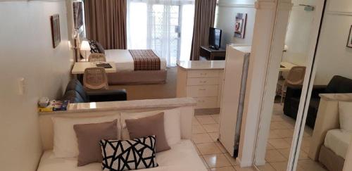 a living room with a couch and a bedroom at Reef Palms in Cairns