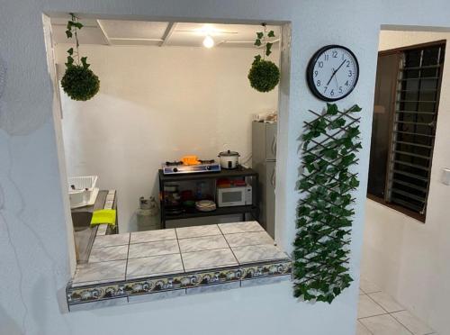 a room with a clock on the wall and a kitchen at Casa Valeria in Puntarenas