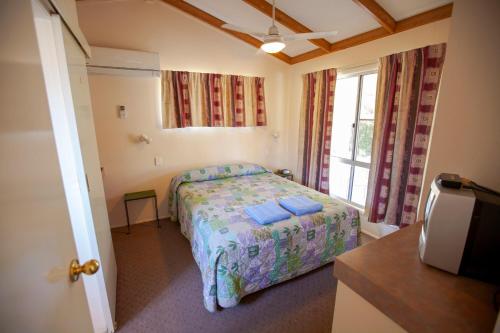 1 dormitorio con cama y ventana en Mitchell Motel & Cabin Park, en Mitchell