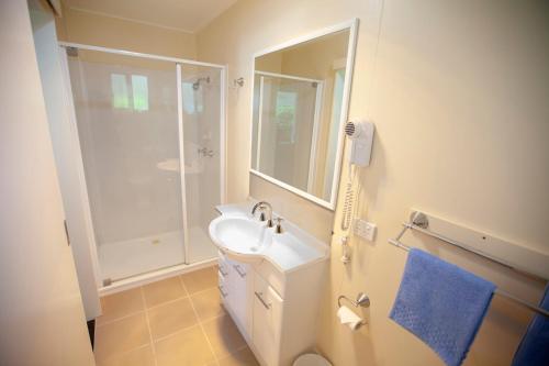 ein weißes Bad mit einem Waschbecken und einer Dusche in der Unterkunft Mitchell Motel & Cabin Park in Mitchell