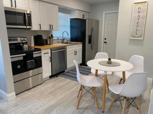 a kitchen with a white table and chairs and a table and a kitchen with at Lovely 2-Bedrooms Central Clearwater Apartment in Clearwater
