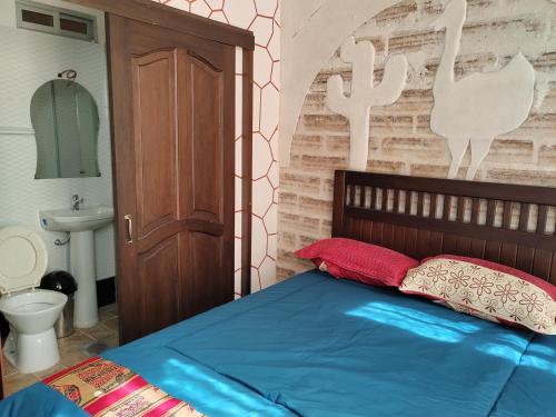 1 dormitorio con 1 cama con sábanas azules y almohadas rojas en Uyuni HOSTAL YOKOSO en Uyuni