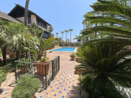 un complexe avec une piscine et des palmiers dans l'établissement Villa puerto banuus Marbella, à Marbella