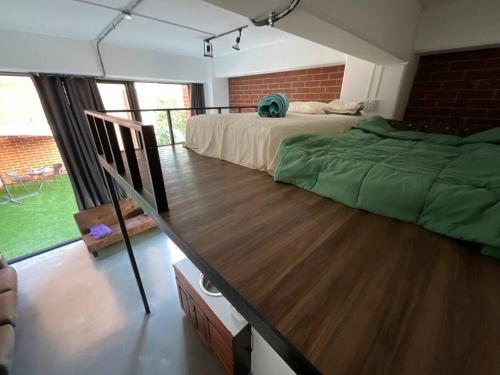 een slaapkamer met 2 bedden en een houten vloer bij Cómodo loft en centro de zona 4 in Guatemala