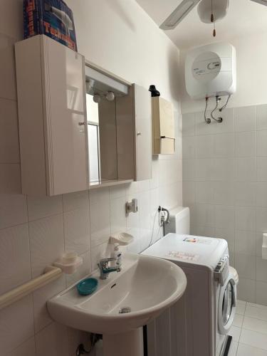 ein weißes Badezimmer mit einem Waschbecken und einem Kühlschrank in der Unterkunft Perla Marina in Capitolo