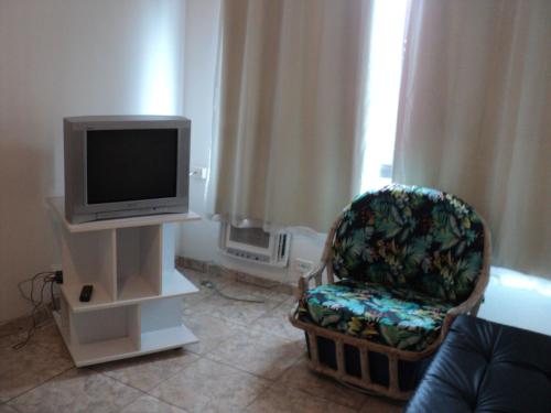 a living room with a tv and a chair at Apartamento Aconchegante in São Vicente