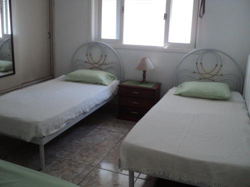 a bedroom with two beds and a lamp and two windows at Apartamento Aconchegante in São Vicente