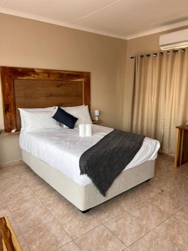 a bedroom with a large bed with a wooden headboard at The Botanical Gardens in Rundu