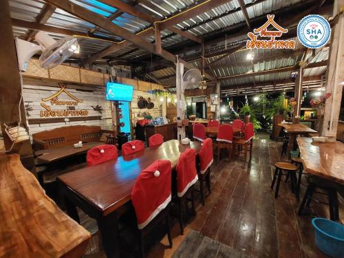 un restaurante con mesas de madera y sillas rojas en Rapeepat Residential and Resort en Ban Nong Khaman