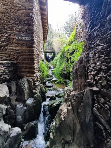 un ruisseau traversant un mur en pierre à côté d'une cascade dans l'établissement Susurros del Manadero, à Robledillo de Gata