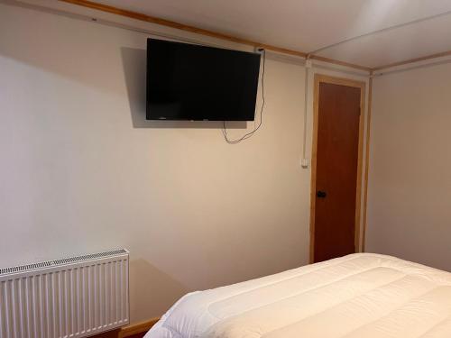 a bedroom with a flat screen tv on the wall at Hostal B&B Coastal Natales in Puerto Natales