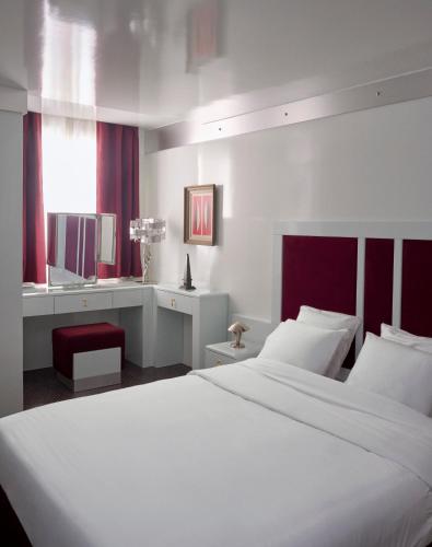 une chambre avec un grand lit blanc et une chaise rouge dans l'établissement Pied A Terre Arts et Métiers, à Paris