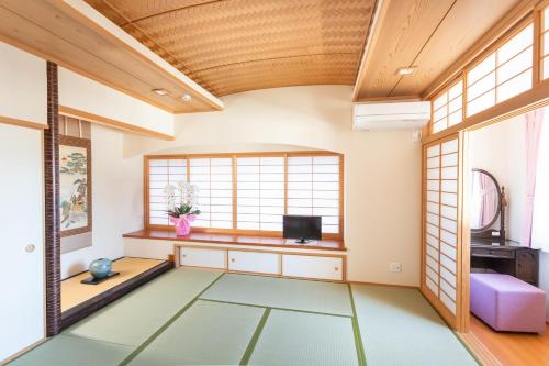 a living room with a large window and a tv at Miyajima Fujinoya Female Only in Miyajima