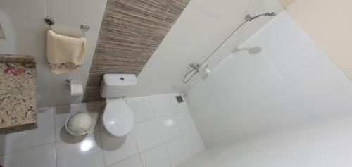 a white bathroom with a toilet and a sink at Tower Suites in Paraguarí
