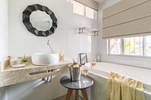 ein Badezimmer mit einer Badewanne, einem Waschbecken und einem Spiegel in der Unterkunft Pinheira Beach House com Jacuzzi in Palhoça
