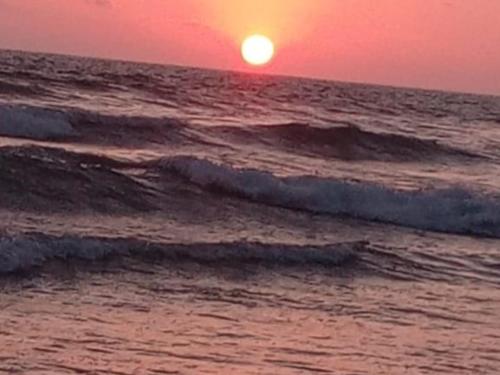 una puesta de sol sobre el océano con olas en el agua en Estancias De Olon, en Olón