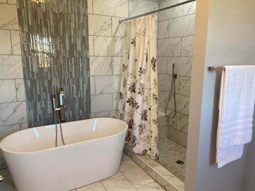 a white bath tub in a bathroom with a shower at La Casa Grande Hosting in Whitsett