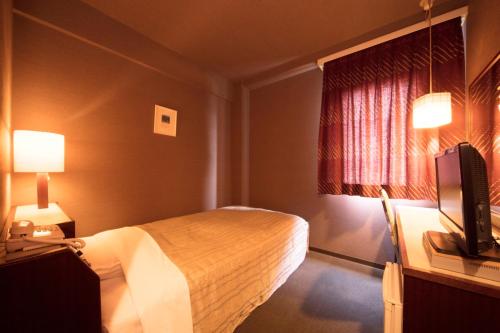 a hotel room with a bed and a television at Plaza Inn Mizusawa in Oshu