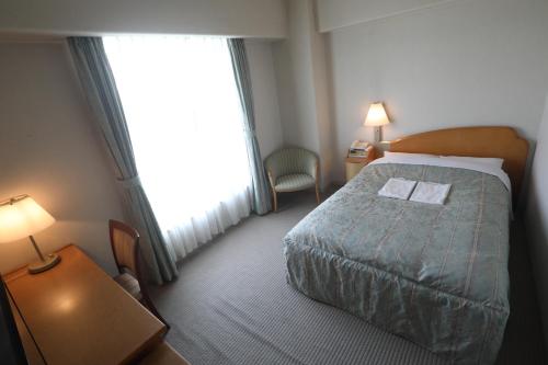 a hotel room with a bed and a window at Plaza Inn Mizusawa in Oshu