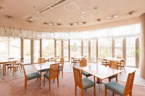 ein Restaurant mit Tischen, Stühlen und Fenstern in der Unterkunft Plaza Inn Mizusawa in Oshu