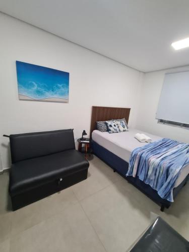 une chambre avec un lit et un canapé dans l'établissement Loft em prédio em frente à praia, à Santos