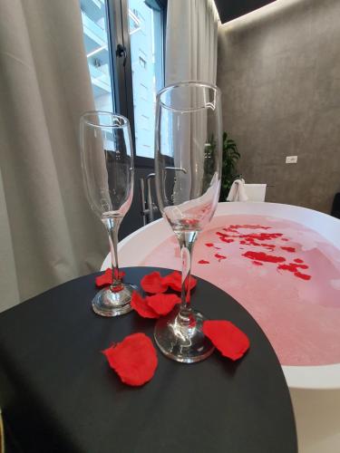 zwei Weingläser und rote Blumen auf dem Tisch in der Unterkunft Vlore Luxury Apartaments "FAEL" in Vlorë