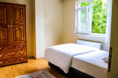 a bedroom with a bed and a dresser and a window at شقة أوزنجول 3 in Çaykara