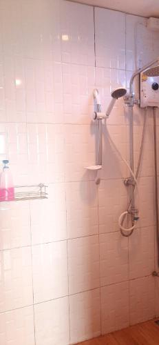 a shower in a bathroom with a white tiled wall at Yafin khaokho Camping in Ban Pa Daeng