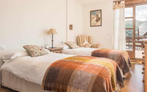 1 dormitorio con 2 camas con mantas en Snow y Bike Formigal, en Formigal