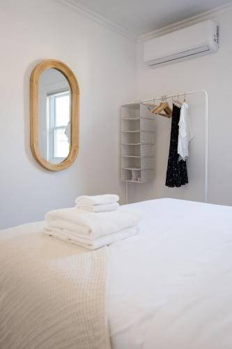 a white room with a bed and a mirror at The Darcie House - cozy, pet-friendly home in PEC in Picton