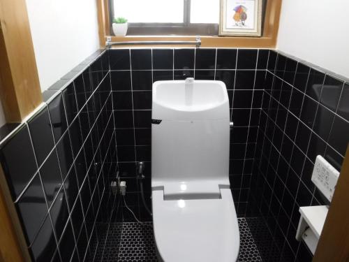 a white toilet in a bathroom with black tiles at Bob's house - Vacation STAY 42876v in Kameoka