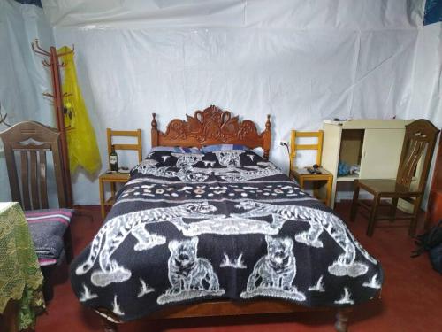 a bedroom with a bed with a black and white blanket at Posada Shumac Ñahui baño privado y ducha caliente in Huaraz