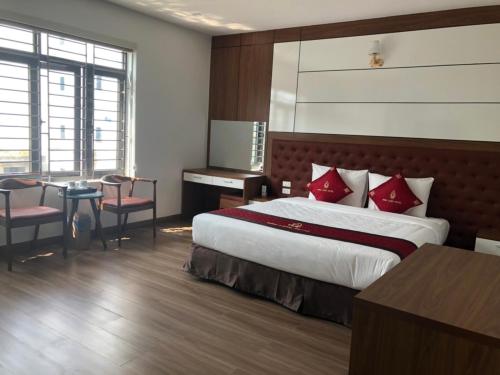 Bình Long II Hotel في Lai Châu: غرفة نوم بسرير كبير ومخدات حمراء