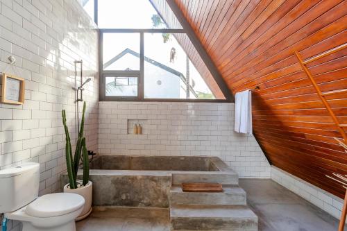 a bathroom with a tub and a toilet and a window at Modern 2 BR Villa Indra by Azure, in the Lap of Nature in Munggu