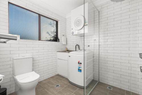 a white bathroom with a toilet and a sink at Orana by Experience Jervis Bay in Vincentia
