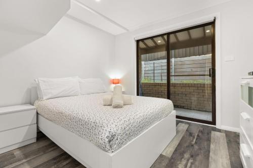 a white bedroom with a white bed and a window at Orana by Experience Jervis Bay in Vincentia
