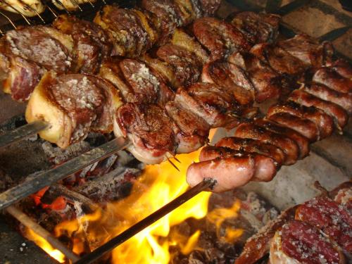 a bunch of meat and sausage on a grill at Apartamento Enseada Náutico Caldas Novas - GO in Caldas Novas