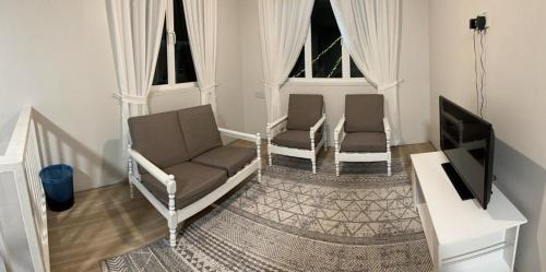 een woonkamer met 2 stoelen en een flatscreen-tv bij Qloud Cottage in Ranau