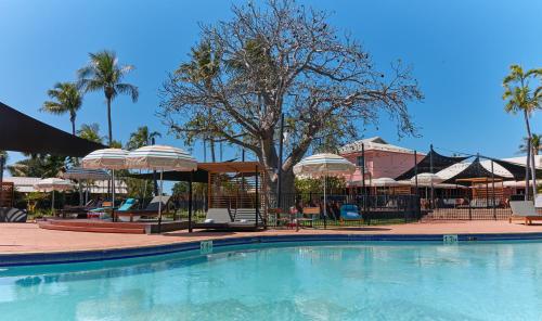 a swimming pool with chairs and umbrellas at The Continental Hotel in Broome