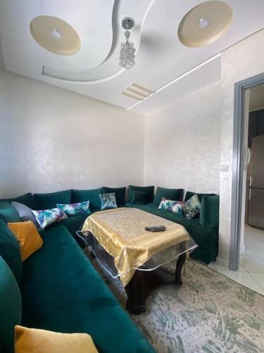 un soggiorno con divano verde e tavolo di Appartement familial 1 - Cité essalam ad Agadir