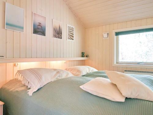 a bedroom with two beds with pillows and a window at Holiday home Nexø X in Vester Sømarken