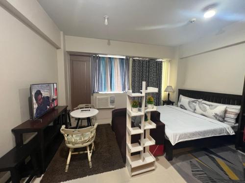 a bedroom with a bed and a desk and a table at One Palmtree Villas Airport Condo in Manila