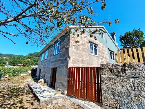 an old stone house with a red gate at El Mirador de playa LAPAMAN - BUEU in Marín
