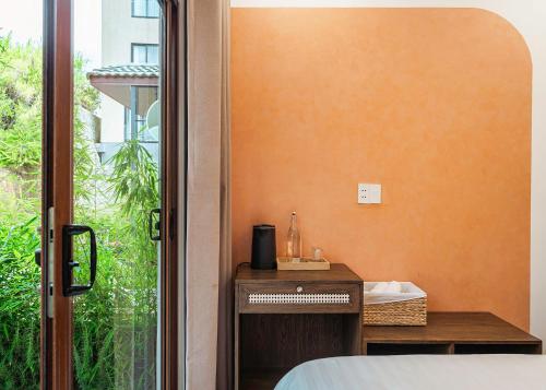 a bedroom with an orange wall and a bed and a window at Miền Sương Khói - Home & Café in Khu Chi Lăng