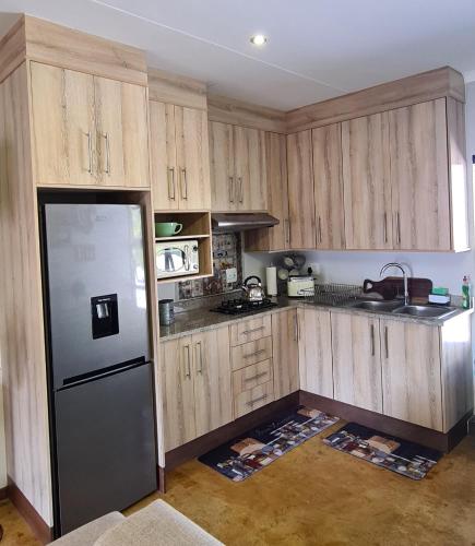 a kitchen with wooden cabinets and a refrigerator at Upstairs R-2 Self-Catering Unit in White River