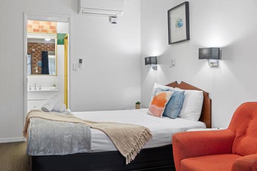 a bedroom with a bed and a orange chair at Airport Clayfield Motel in Brisbane