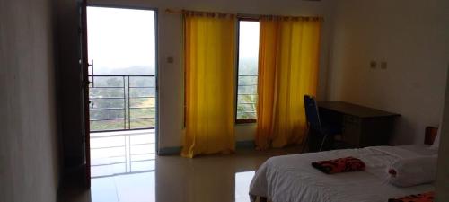 een slaapkamer met een bed en een raam met gele gordijnen bij FARILA LODGE in Ende