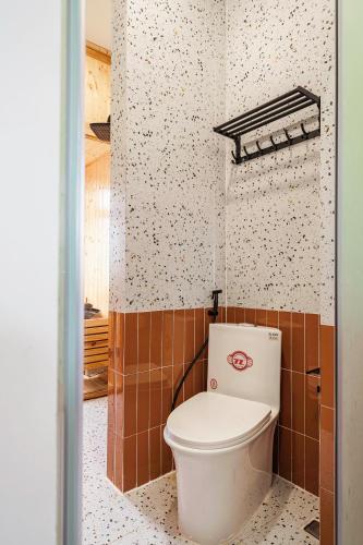 a bathroom with a toilet in a tiled wall at Miền Sương Khói - Home & Café in Khu Chi Lăng