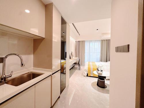 uma cozinha com um lavatório e um quarto com uma cama em Canopy Executive Apartments - Liuxian Cave Headquarters em Shenzhen