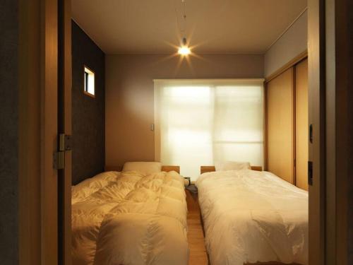 富士吉田的住宿－Renewal Open! 【urban’s camp fuji】ウッドデッキでBBQ可！新装別荘！，卧室设有两张单人床和窗户。